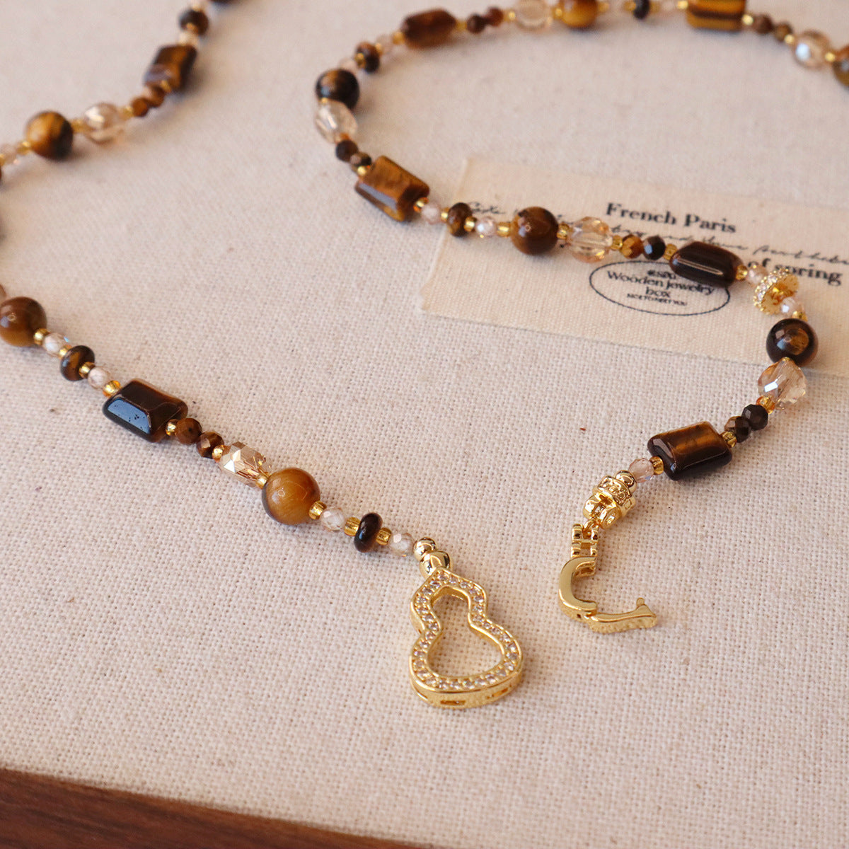 Detail of zircon-studded calabash charm on tiger eye sweater chain