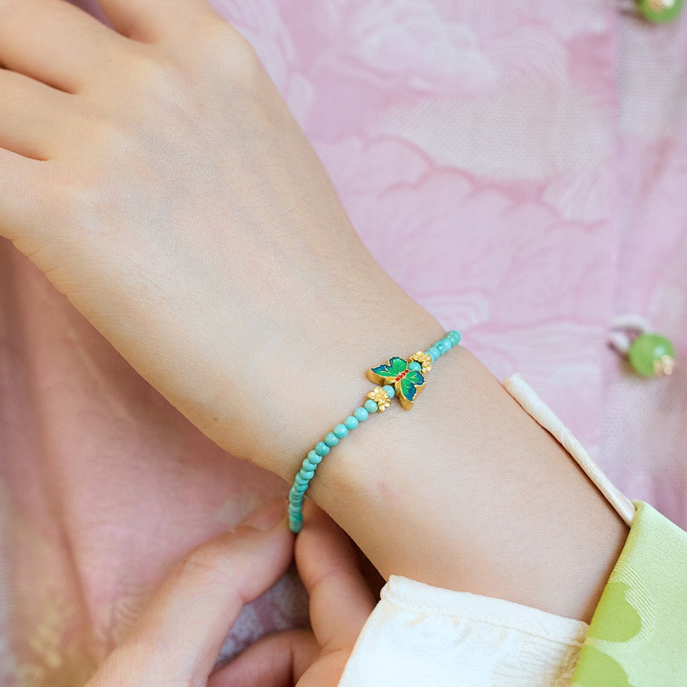 Detail of natural turquoise bracelet with enamel butterfly pendant