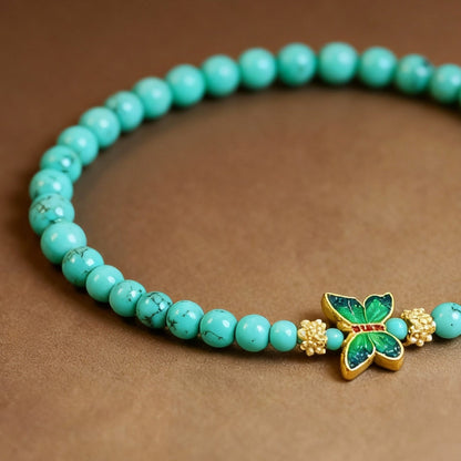 Close-up of turquoise beads with colorful enamel butterfly charm