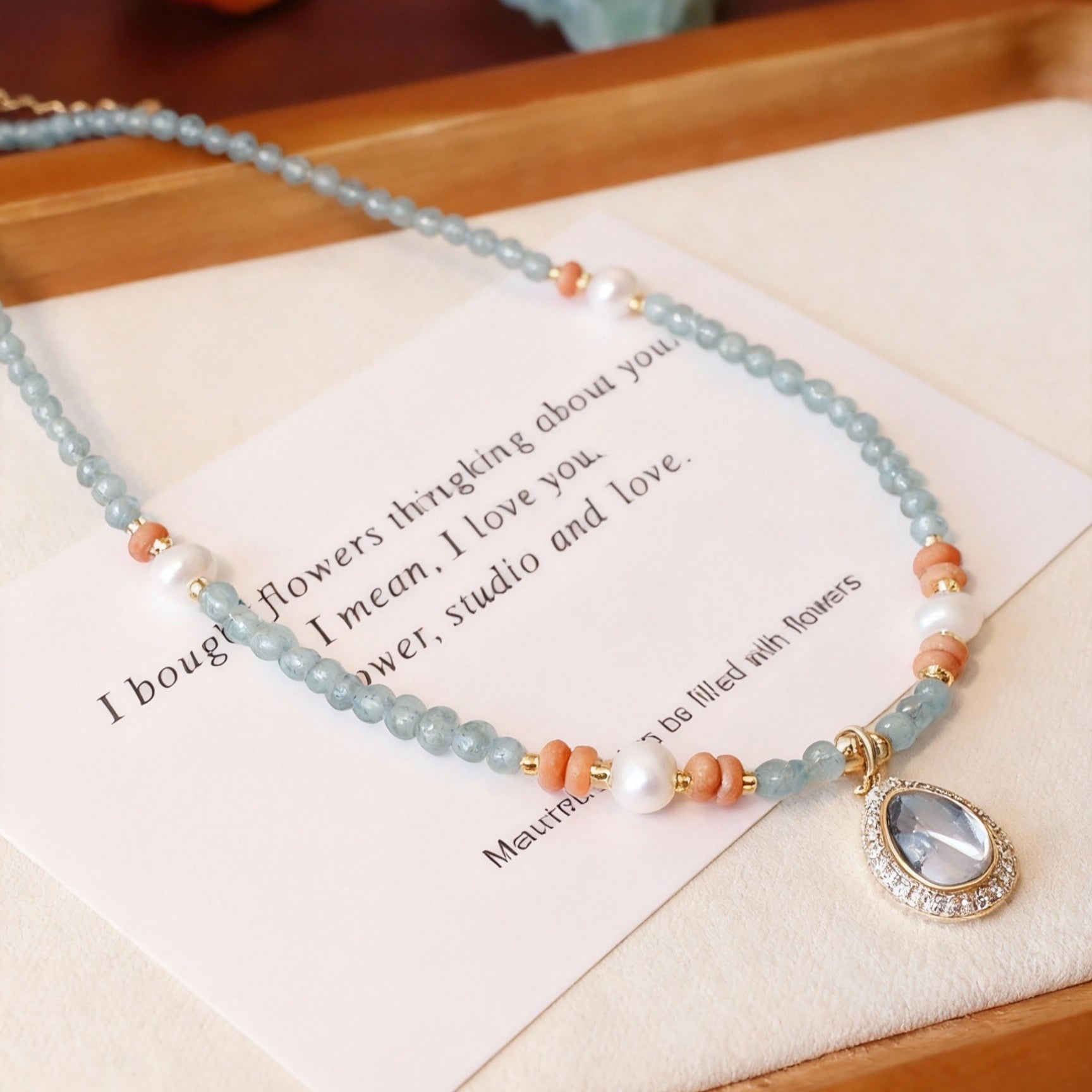 Detail of blue aquamarine ocean heart necklace with pearl beads