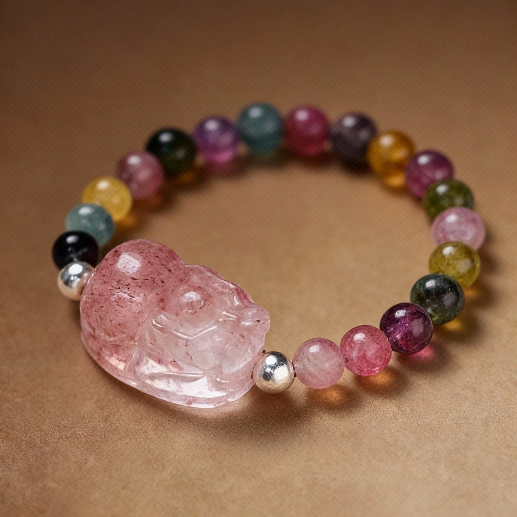 Close-up of tourmaline ring with Pixiu charm and pink strawberry quartz